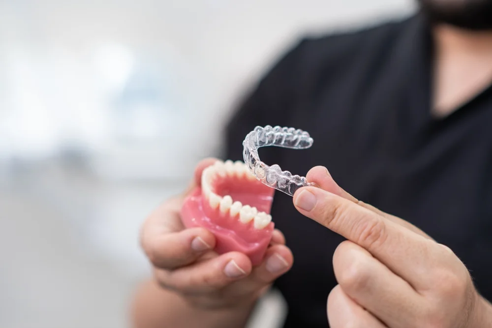 Clear Aligners (2) Hand placing a clear aligner over a dental arch model during an orthodontic consultation at Parramatta Green Dental.