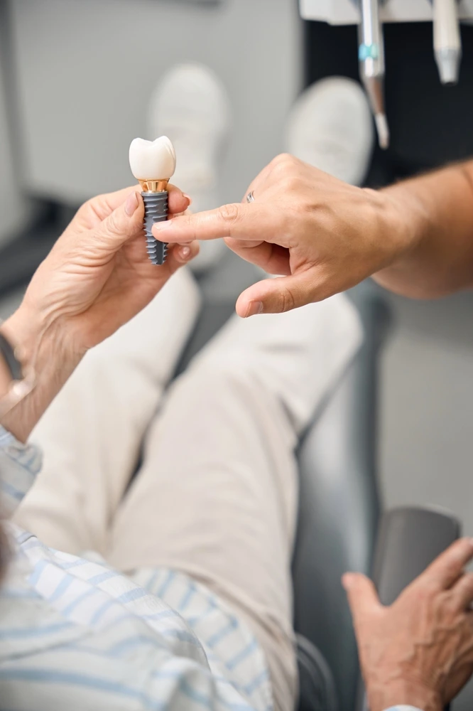 Patient examining a realistic dental implant model during a treatment discussion at Parramatta Green Dental.